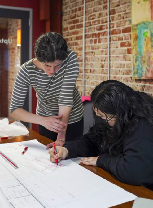 Yasemin Tarhan facilitating a workshop, sketching over drawings with a participant